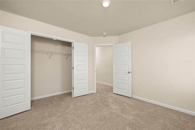 unfurnished bedroom featuring light carpet and a closet