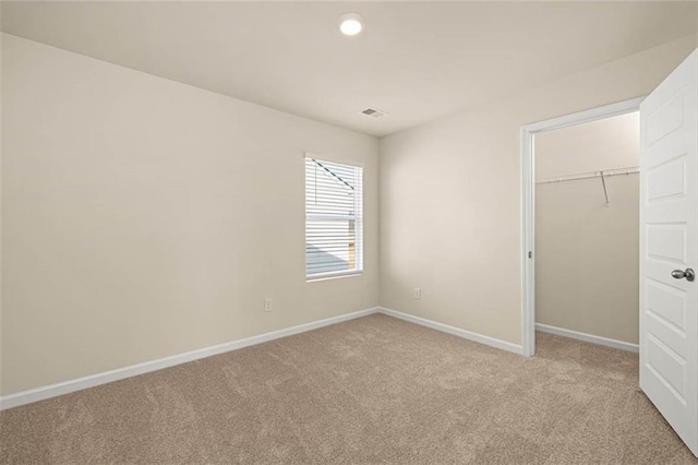 unfurnished bedroom with light colored carpet and a closet