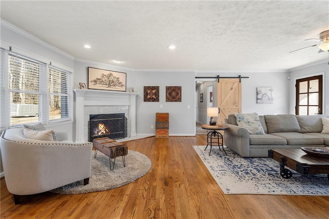 living room with a fireplace, ornamental molding, a textured ceiling, and light hardwood / wood-style floors