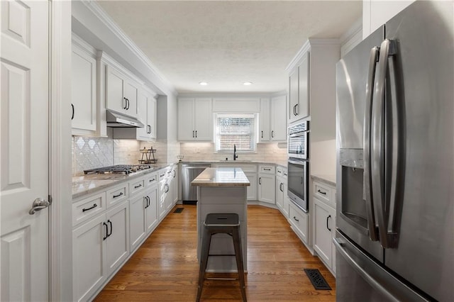 kitchen featuring appliances with stainless steel finishes, sink, white cabinetry, and a kitchen island