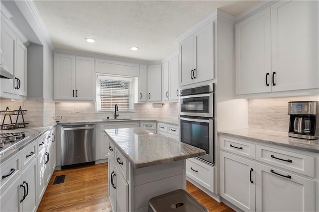 kitchen with tasteful backsplash, white cabinetry, stainless steel appliances, and a kitchen island