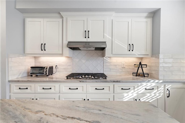 kitchen featuring ventilation hood, stainless steel gas cooktop, backsplash, and white cabinets