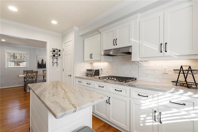 kitchen with white cabinetry, stainless steel gas cooktop, wood-type flooring, light stone countertops, and crown molding