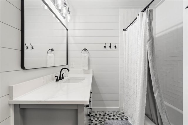 bathroom with vanity, wooden walls, and shower / bath combo with shower curtain