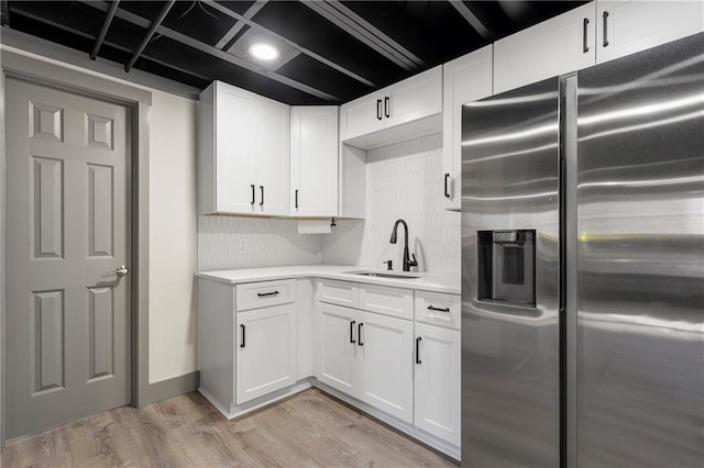 kitchen with light hardwood / wood-style floors, decorative backsplash, sink, white cabinetry, and stainless steel fridge with ice dispenser