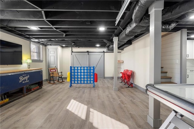 rec room with a barn door and wood-type flooring