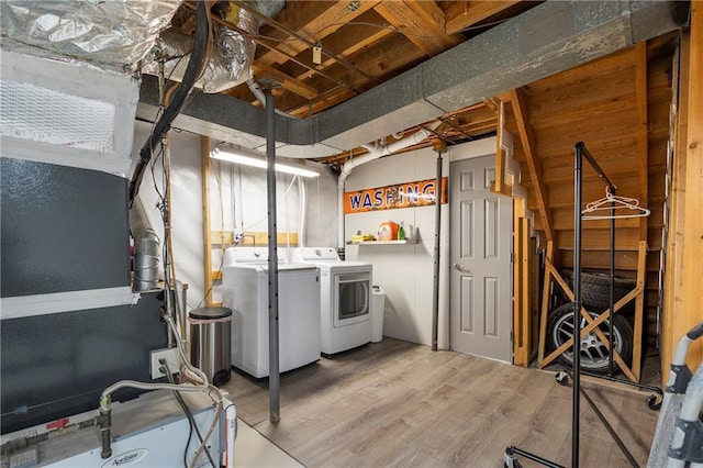 clothes washing area with washing machine and dryer and hardwood / wood-style flooring