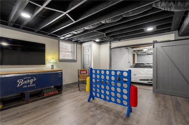 basement with hardwood / wood-style flooring and a barn door