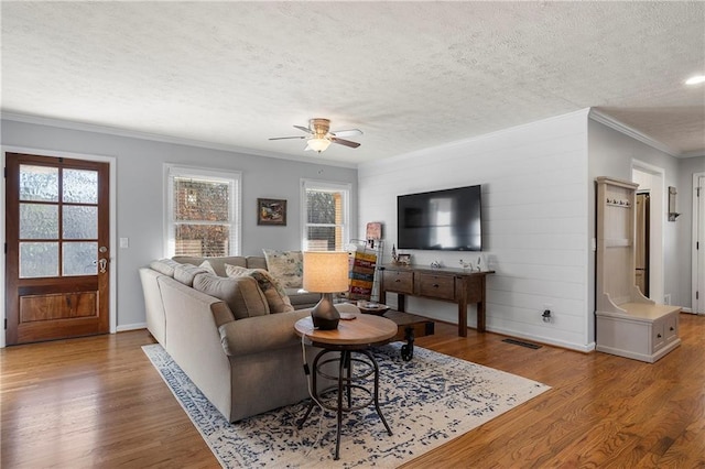 living room featuring ceiling fan, crown molding, a textured ceiling, and light hardwood / wood-style flooring