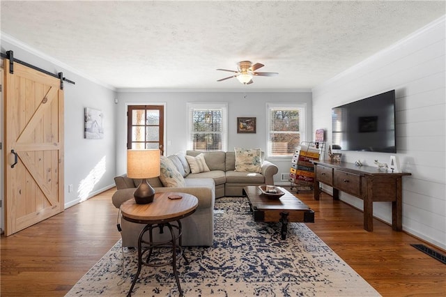 living room featuring hardwood / wood-style floors, a textured ceiling, ornamental molding, and a barn door