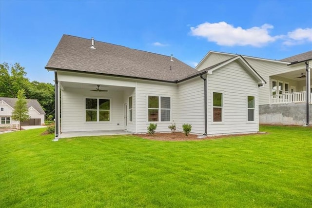 rear view of property featuring a ceiling fan, a yard, and a shingled roof