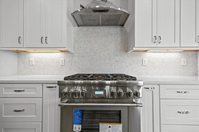 kitchen with tasteful backsplash, range hood, white cabinets, and high end range