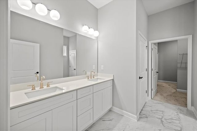 bathroom featuring marble finish floor, a sink, baseboards, and double vanity