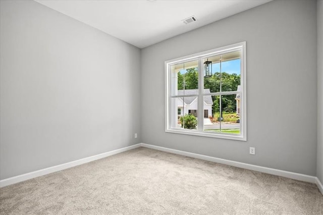 carpeted empty room featuring baseboards and visible vents