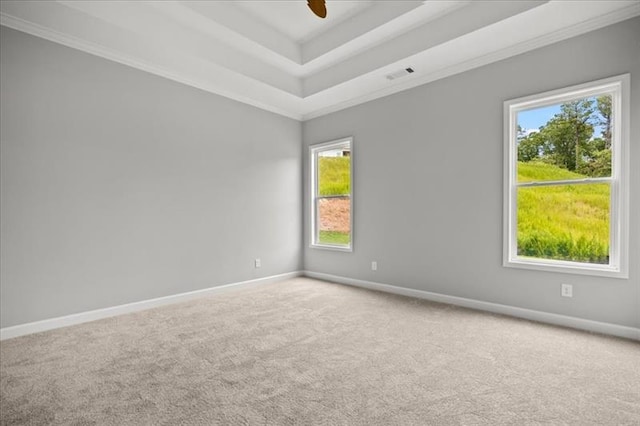 carpeted empty room featuring a tray ceiling, a ceiling fan, visible vents, and baseboards