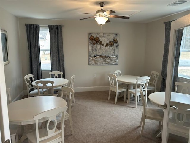 carpeted dining room with a ceiling fan, visible vents, and baseboards