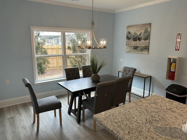 dining room featuring a chandelier, crown molding, baseboards, and wood finished floors