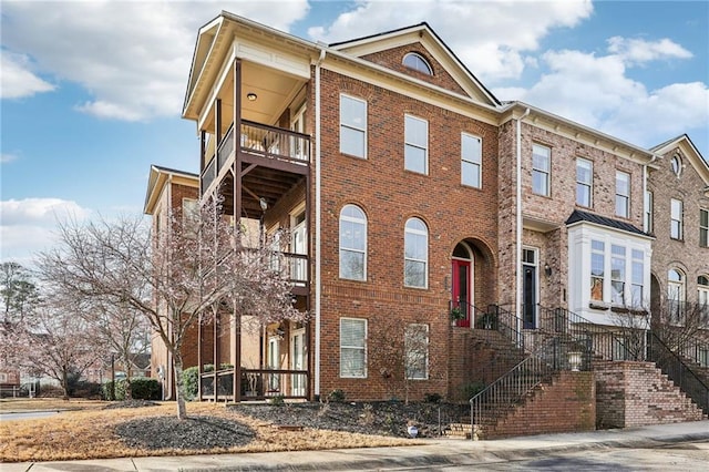 view of property featuring a balcony and brick siding