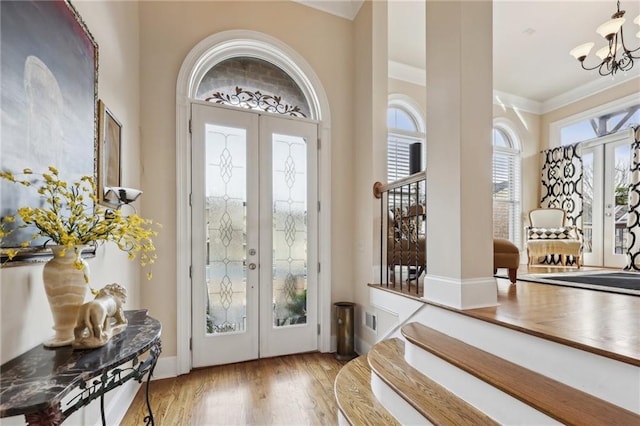 entryway with wood finished floors, an inviting chandelier, stairs, crown molding, and french doors