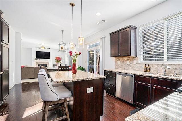 kitchen with decorative backsplash, light stone countertops, a breakfast bar, dishwasher, and a kitchen island