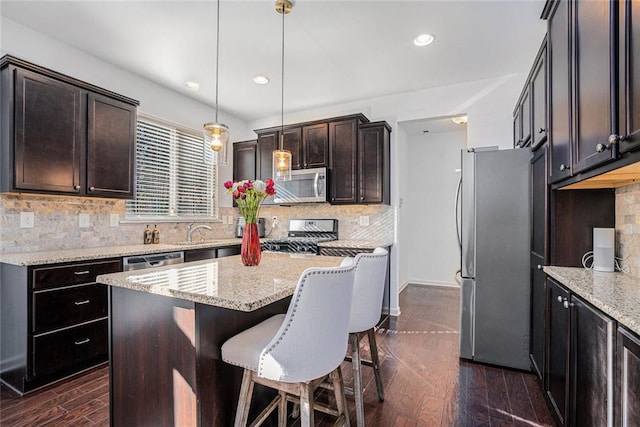 kitchen featuring tasteful backsplash, a center island, stainless steel appliances, and decorative light fixtures