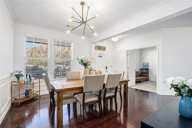 dining space with crown molding, dark hardwood / wood-style floors, and an inviting chandelier