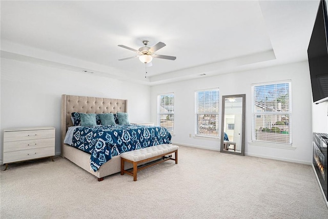 carpeted bedroom with a tray ceiling and ceiling fan