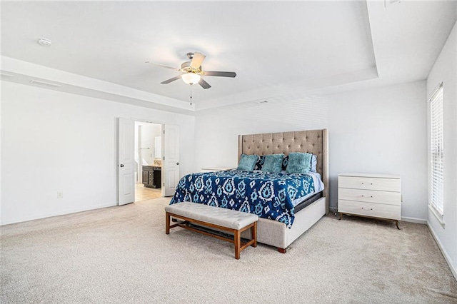 carpeted bedroom with connected bathroom, a tray ceiling, and ceiling fan