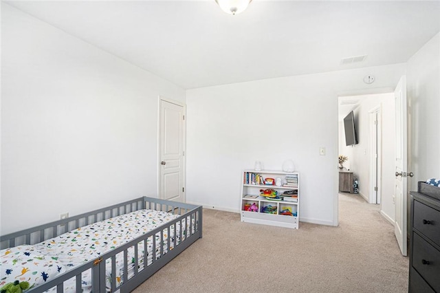 bedroom featuring light colored carpet and a nursery area