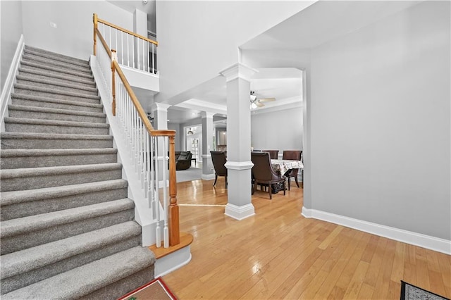 stairs featuring decorative columns, ceiling fan, and hardwood / wood-style flooring