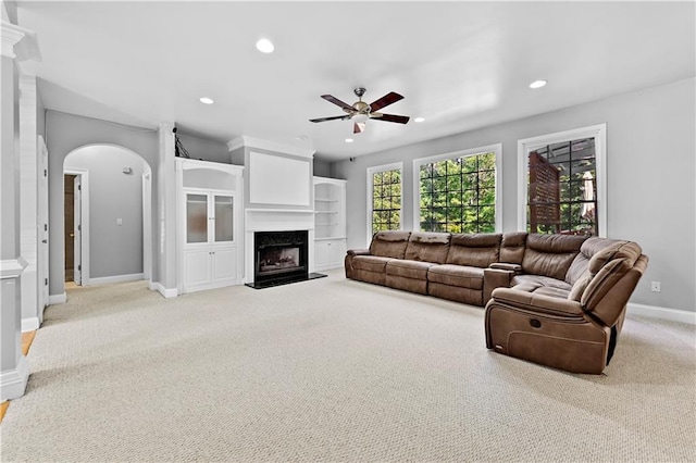 living room featuring ceiling fan, a fireplace, and light colored carpet