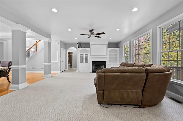 carpeted living room featuring ceiling fan and decorative columns