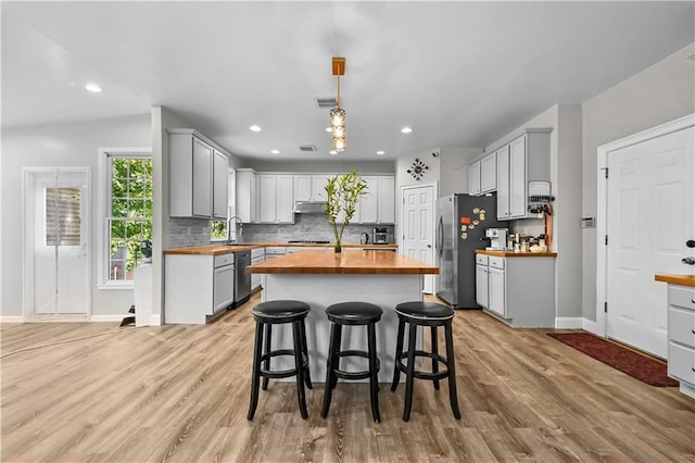 kitchen featuring wood counters, stainless steel appliances, hanging light fixtures, and light hardwood / wood-style flooring