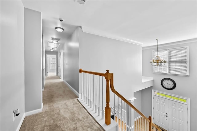 corridor with crown molding, light colored carpet, and an inviting chandelier