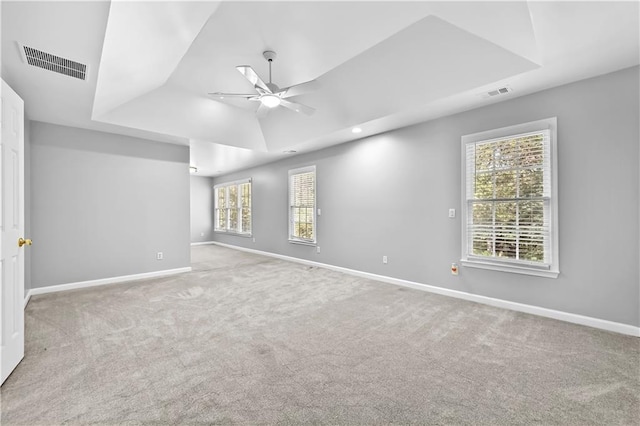 carpeted spare room featuring a raised ceiling and ceiling fan