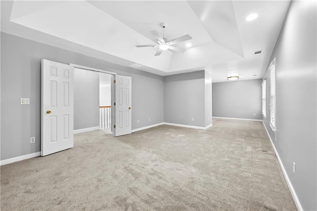 carpeted spare room featuring ceiling fan and a tray ceiling