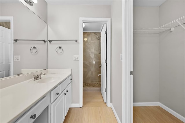 bathroom with vanity, wood-type flooring, and tiled shower