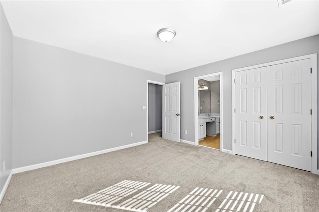 unfurnished bedroom featuring ensuite bath, light carpet, and a closet