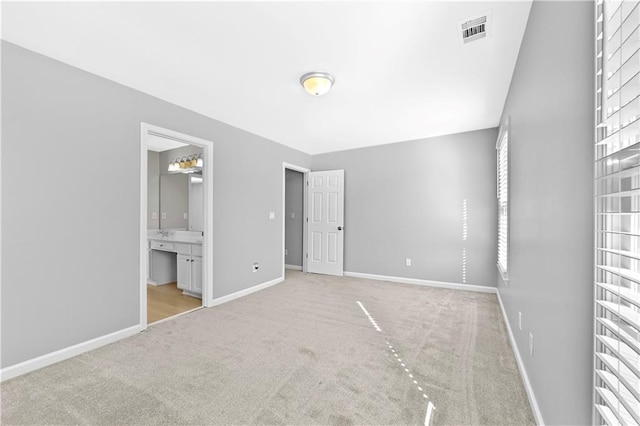 unfurnished bedroom with connected bathroom and light carpet