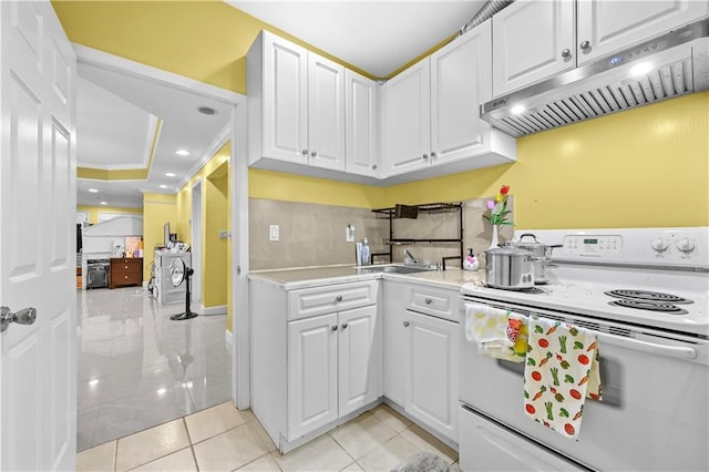 kitchen featuring a tray ceiling, sink, light tile patterned floors, electric range, and white cabinets