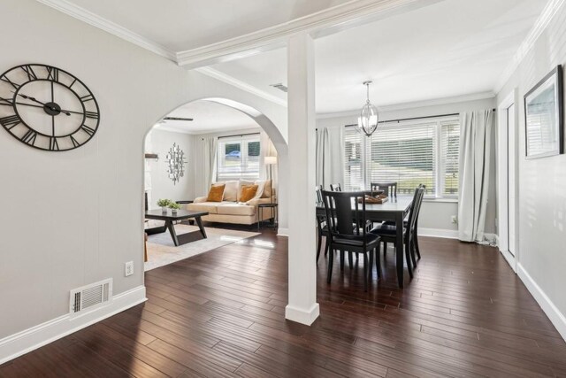 dining space with an inviting chandelier, ornamental molding, a healthy amount of sunlight, and dark hardwood / wood-style flooring