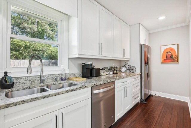 kitchen with dark hardwood / wood-style floors, stainless steel appliances, ornamental molding, sink, and white cabinets