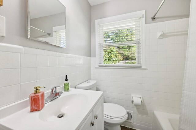 full bathroom with tile walls, vanity, shower / tub combo with curtain, and toilet