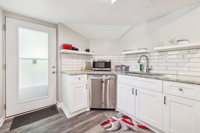 kitchen featuring white cabinets, backsplash, appliances with stainless steel finishes, light hardwood / wood-style floors, and sink