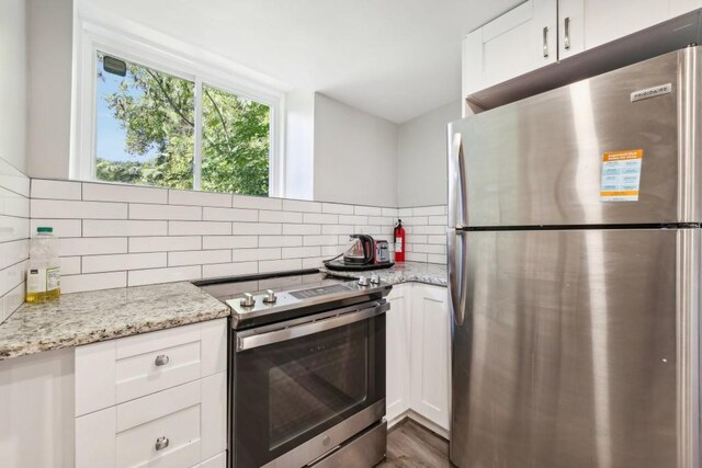 kitchen with appliances with stainless steel finishes, white cabinets, and light stone countertops