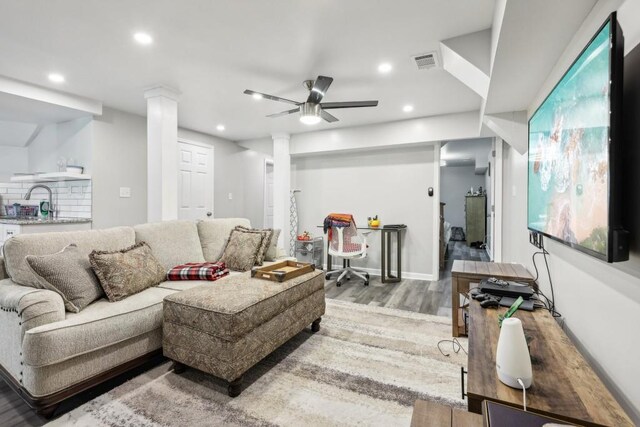 living room featuring ornate columns, ceiling fan, and hardwood / wood-style floors