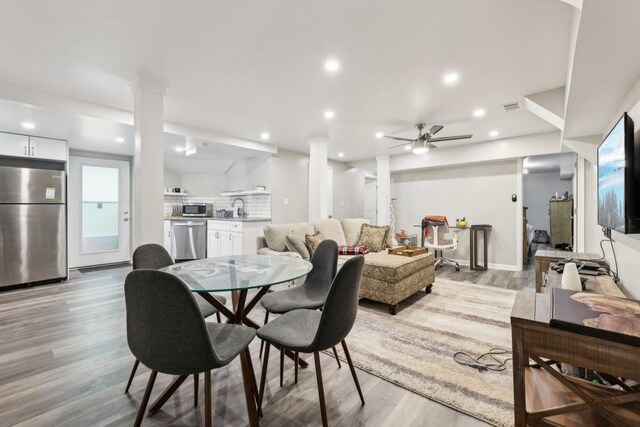 dining area with sink, ceiling fan, decorative columns, and light hardwood / wood-style flooring