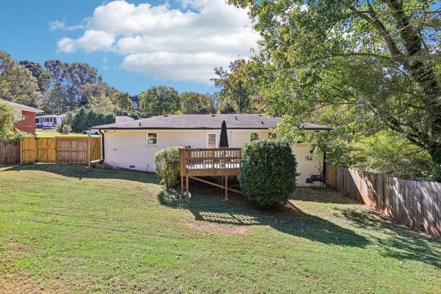 back of property with a deck and a lawn