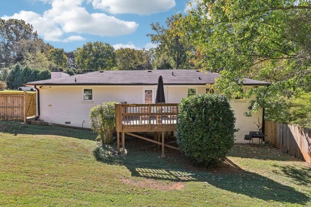 back of house featuring a wooden deck and a lawn