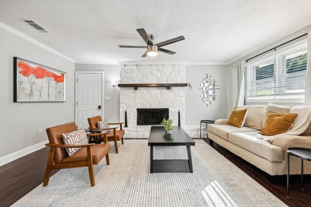 living room featuring ornamental molding, wood-type flooring, a fireplace, and ceiling fan